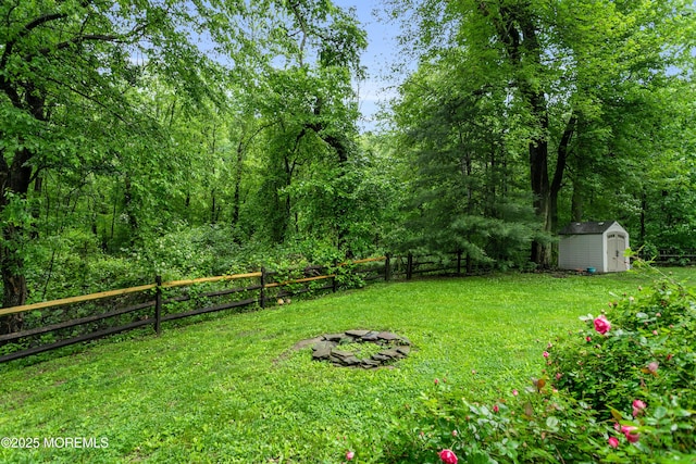 view of yard featuring a shed, an outdoor structure, and a fire pit