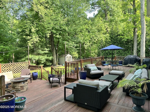 deck featuring an outdoor living space with a fire pit, a shed, area for grilling, an outbuilding, and outdoor dining space