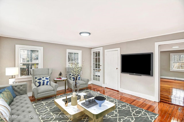 living room featuring hardwood / wood-style floors, ornamental molding, and baseboards