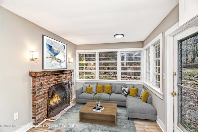 living area featuring wood finished floors, baseboards, and a brick fireplace