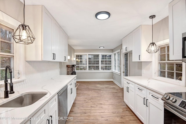 kitchen featuring a sink, stainless steel appliances, baseboards, decorative backsplash, and white cabinets