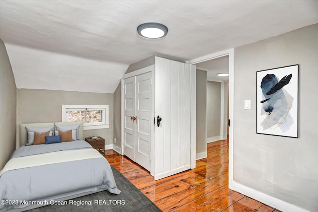 bedroom featuring hardwood / wood-style flooring, baseboards, and lofted ceiling