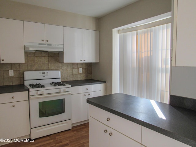 127 Meli Ln, Jackson, NJ 08527 - kitchen with under cabinet range hood, white gas range, dark countertops, decorative backsplash, and white cabinets