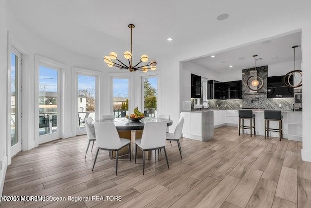 dining area with a chandelier, healthy amount of natural light, light wood-type flooring, and recessed lighting