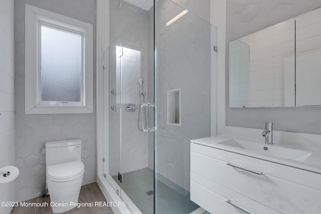 full bath featuring a stall shower, toilet, vanity, and tile walls