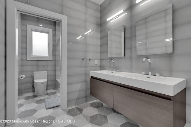 full bathroom with tile walls, toilet, tile patterned flooring, and double vanity