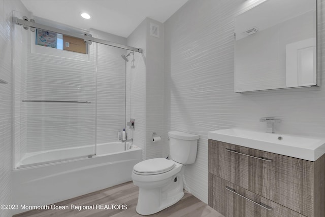 bathroom featuring toilet, tile walls, vanity, bathtub / shower combination, and wood finished floors