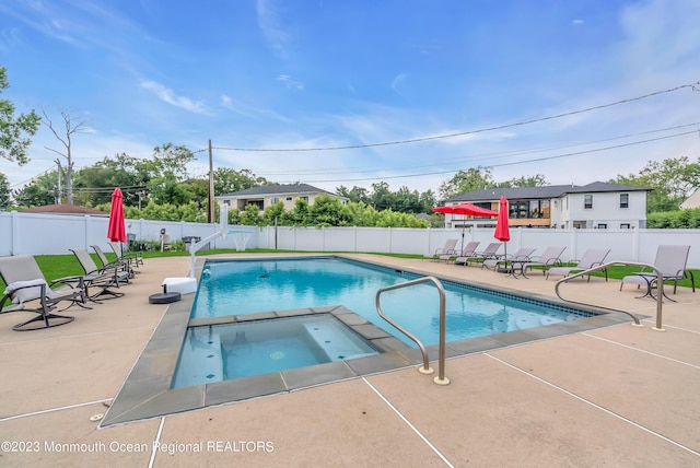 view of pool featuring a patio area, a fenced backyard, and a pool with connected hot tub