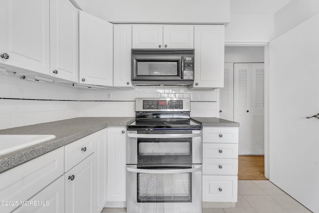 50 Valentine St Unit 14B, Monmouth Beach, NJ 07750 - kitchen with black microwave, range with two ovens, backsplash, and white cabinetry