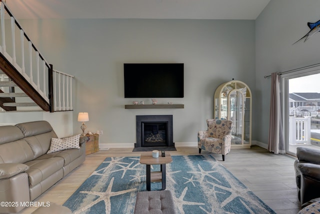 52 Benjamin Blvd, Manahawkin, NJ 08050 - living room featuring light wood-type flooring, baseboards, a fireplace with flush hearth, stairway, and a high ceiling