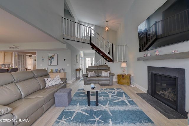 52 Benjamin Blvd, Manahawkin, NJ 08050 - living room with stairway, a fireplace with flush hearth, baseboards, light wood-style flooring, and a towering ceiling