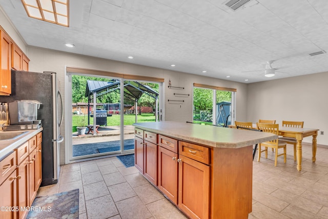 kitchen featuring ceiling fan, light countertops, recessed lighting, a center island, and freestanding refrigerator