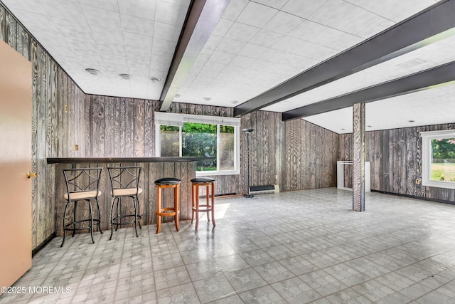 indoor dry bar featuring wood walls, beamed ceiling, tile patterned floors, and baseboards