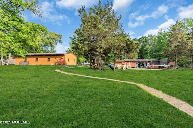 view of grassy yard with a trampoline and a playground