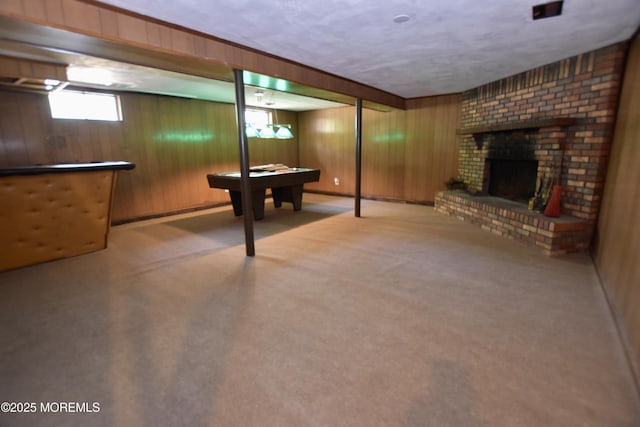 basement with wooden walls, carpet floors, a brick fireplace, and billiards table