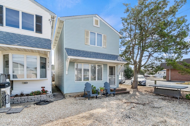 rear view of property with roof with shingles