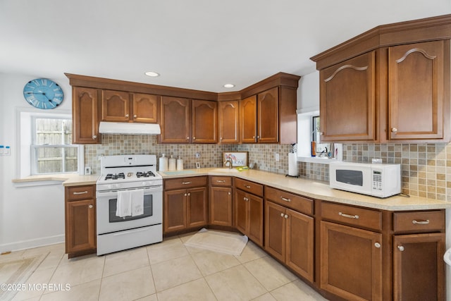 kitchen featuring white appliances, under cabinet range hood, light countertops, tasteful backsplash, and recessed lighting