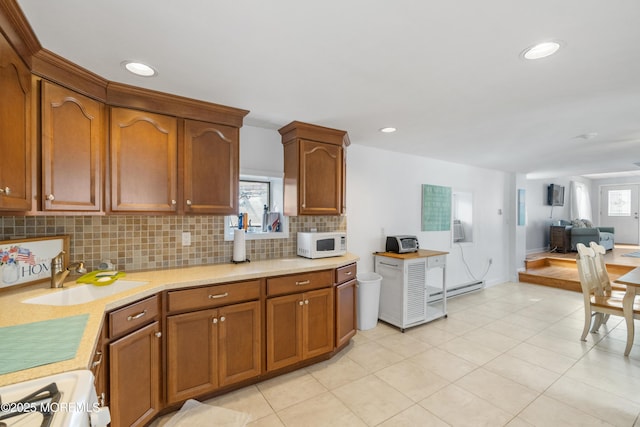 kitchen featuring white microwave, a sink, tasteful backsplash, range, and light countertops