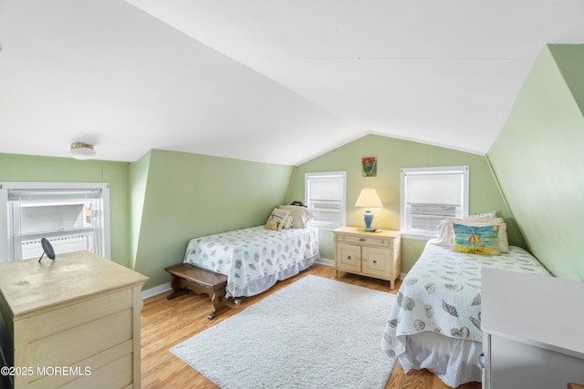 bedroom featuring light wood-style floors, vaulted ceiling, and baseboards