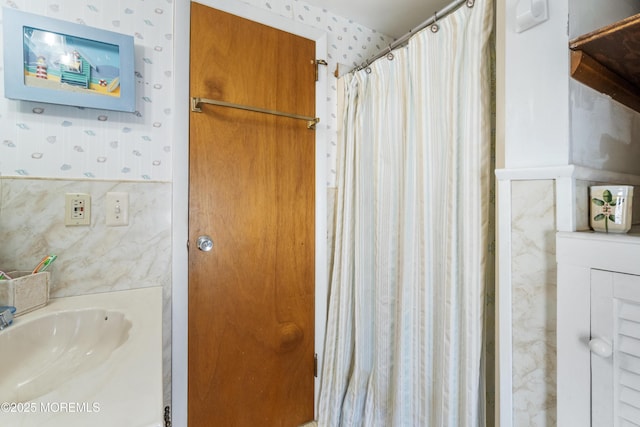 bathroom with wallpapered walls, a sink, and a shower with curtain