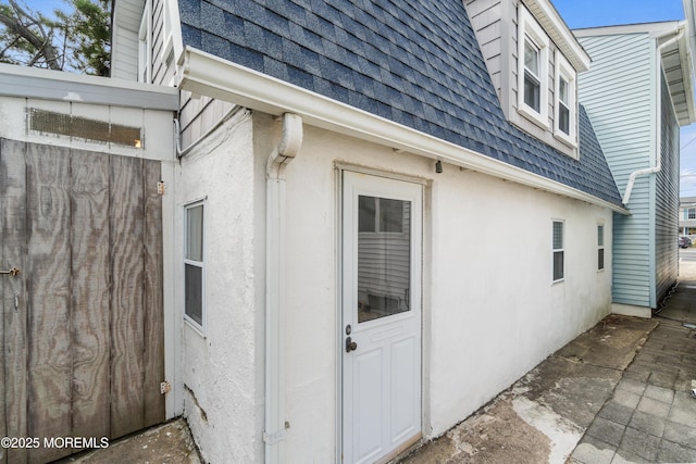 view of side of home with roof with shingles and stucco siding