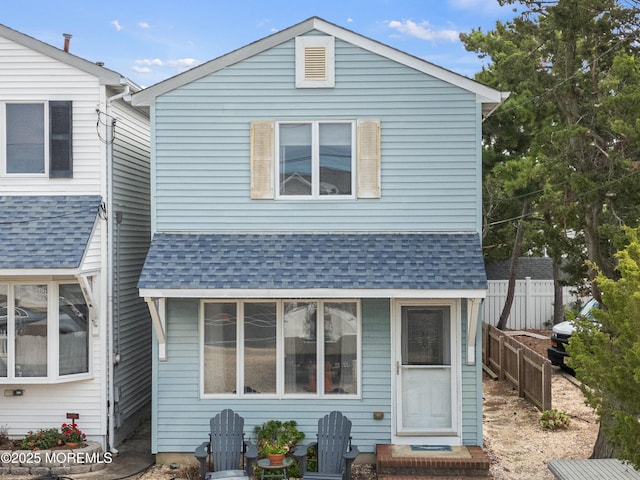 view of front of house with a shingled roof and fence