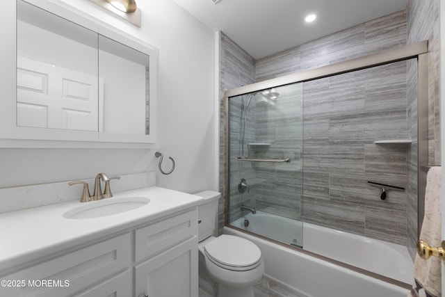full bathroom featuring toilet, shower / bath combination with glass door, and vanity