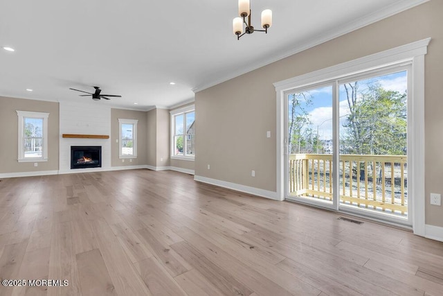 unfurnished living room featuring crown molding, baseboards, a chandelier, light wood finished floors, and a ceiling fan