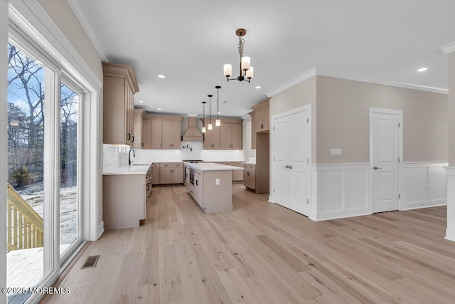 kitchen featuring a sink, stainless steel range oven, a chandelier, light wood-style flooring, and custom exhaust hood