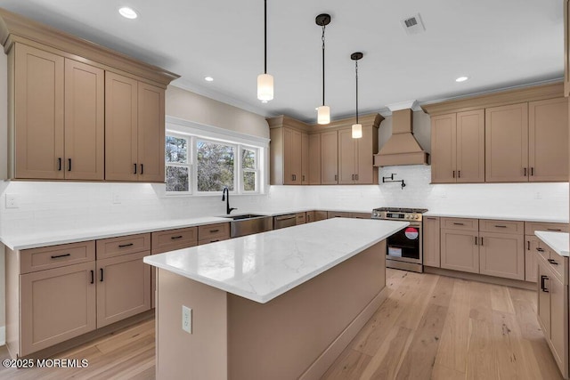kitchen featuring appliances with stainless steel finishes, premium range hood, a kitchen island, light wood-style flooring, and recessed lighting