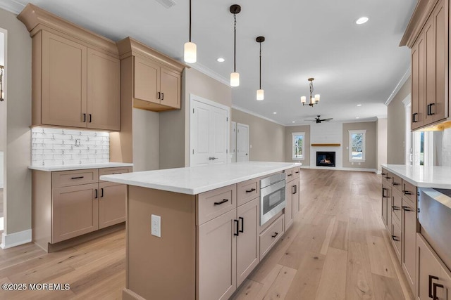 kitchen featuring crown molding, stainless steel microwave, a chandelier, light wood finished floors, and recessed lighting
