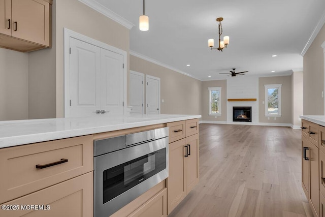 kitchen featuring stainless steel microwave, ornamental molding, a chandelier, light wood-style floors, and a fireplace
