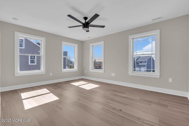 empty room featuring wood finished floors, healthy amount of natural light, and baseboards