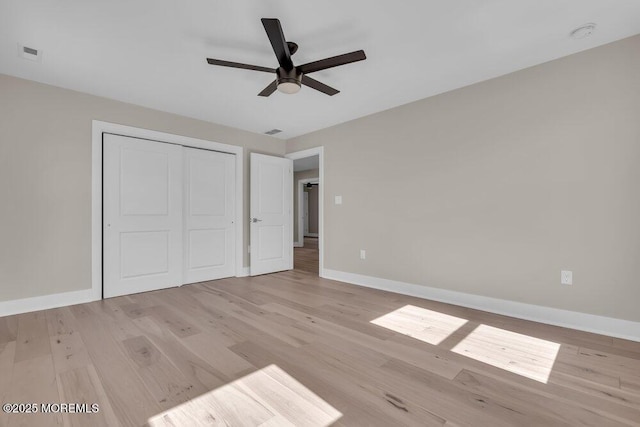 unfurnished bedroom with light wood-type flooring, baseboards, a closet, and a ceiling fan