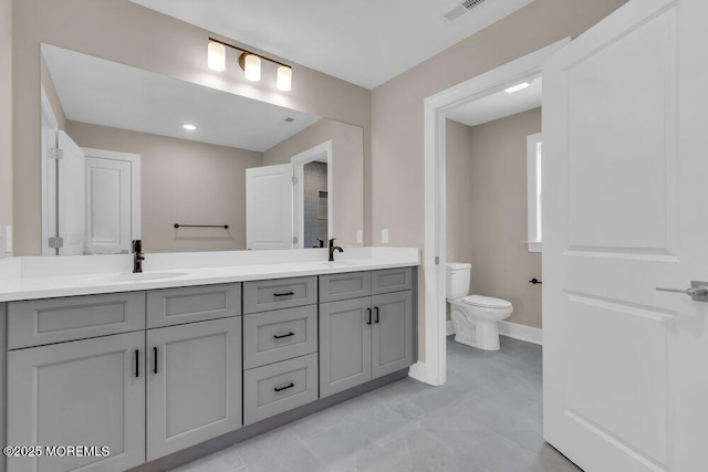 bathroom with toilet, double vanity, and baseboards