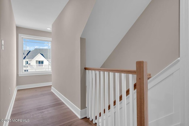 hallway with an upstairs landing, wood finished floors, and baseboards