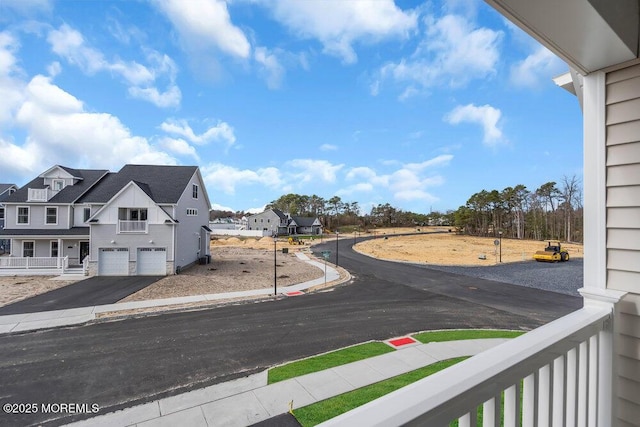 view of asphalt road with sidewalks, curbs, and a residential view