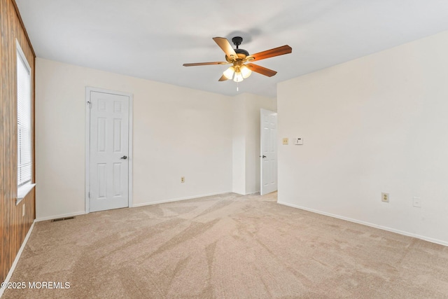 empty room featuring ceiling fan, light colored carpet, and baseboards