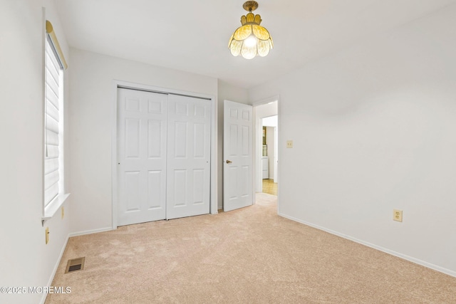 unfurnished bedroom with light carpet, baseboards, and a closet