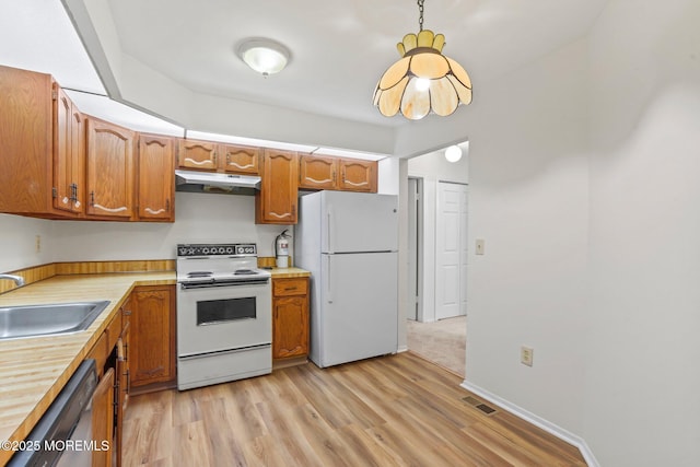 kitchen with white appliances, a sink, under cabinet range hood, light wood-style floors, and light countertops