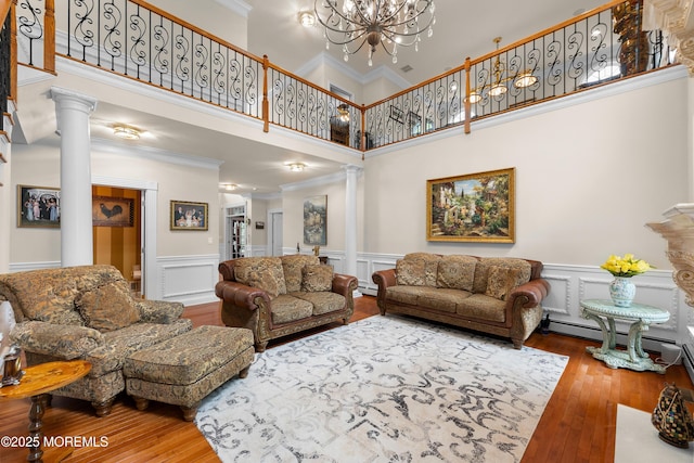 68 Hedgerow Ln, Manalapan, NJ 07726 - living room with decorative columns, wood-type flooring, a chandelier, crown molding, and a towering ceiling