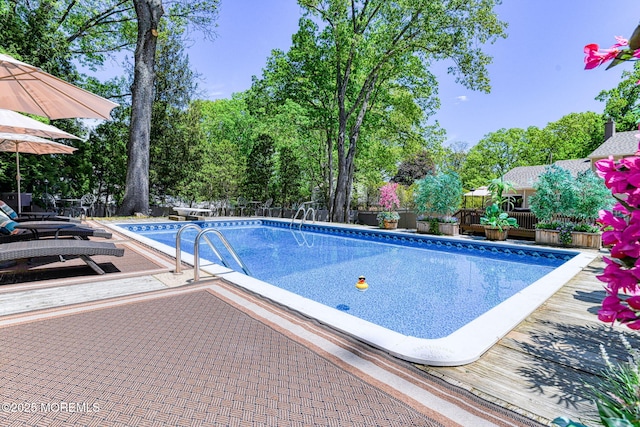 outdoor pool with a fenced backyard and a wooden deck