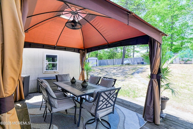 view of patio featuring a gazebo, outdoor dining space, a fenced backyard, and a storage unit