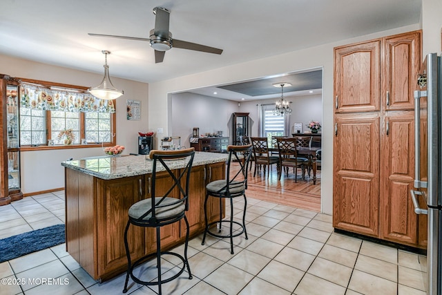 kitchen featuring a center island, a ceiling fan, light tile patterned floors, and hanging light fixtures