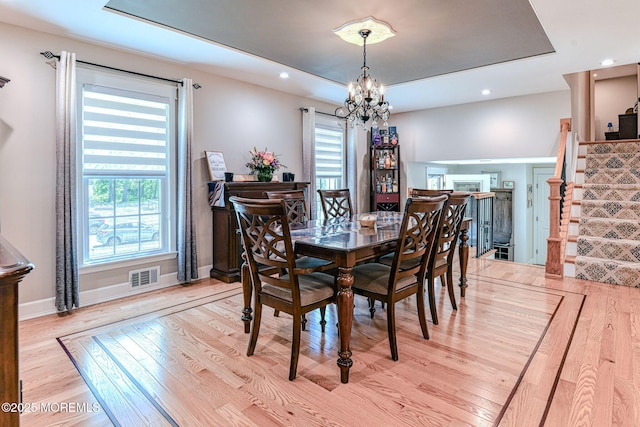 dining room with light wood finished floors, stairway, a chandelier, a tray ceiling, and recessed lighting