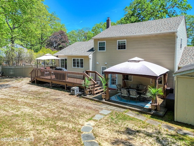 back of house with a gazebo, a deck, a shingled roof, a chimney, and an outdoor hangout area