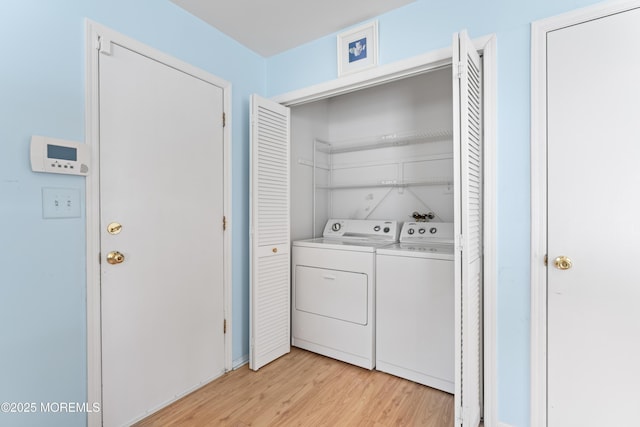 clothes washing area featuring washing machine and clothes dryer and light wood-type flooring
