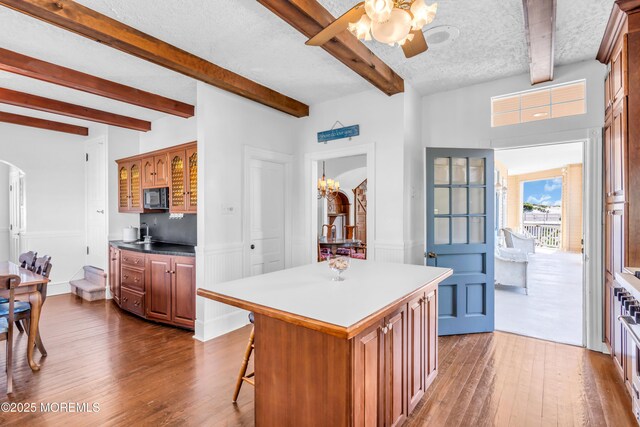 817 S Ocean Ave, Seaside Park, NJ 08752 - kitchen featuring black microwave, arched walkways, dark wood-style floors, beamed ceiling, and a breakfast bar