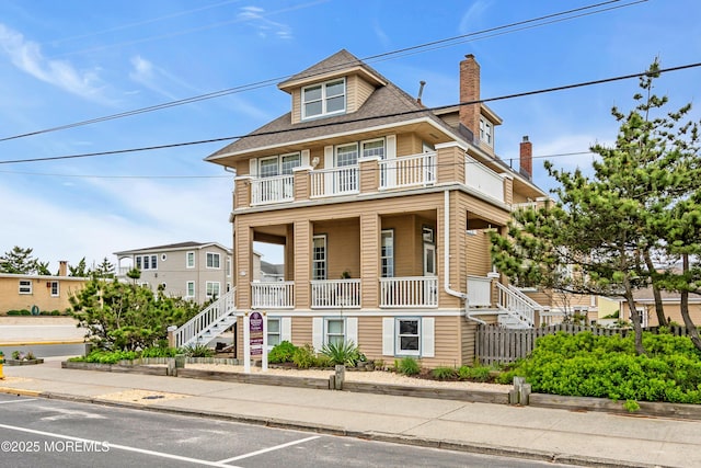 817 S Ocean Ave, Seaside Park, NJ 08752 - view of front of house with stairway, a balcony, covered porch, a chimney, and uncovered parking