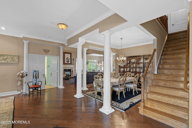 entrance foyer featuring stairs, crown molding, decorative columns, wood finished floors, and a chandelier